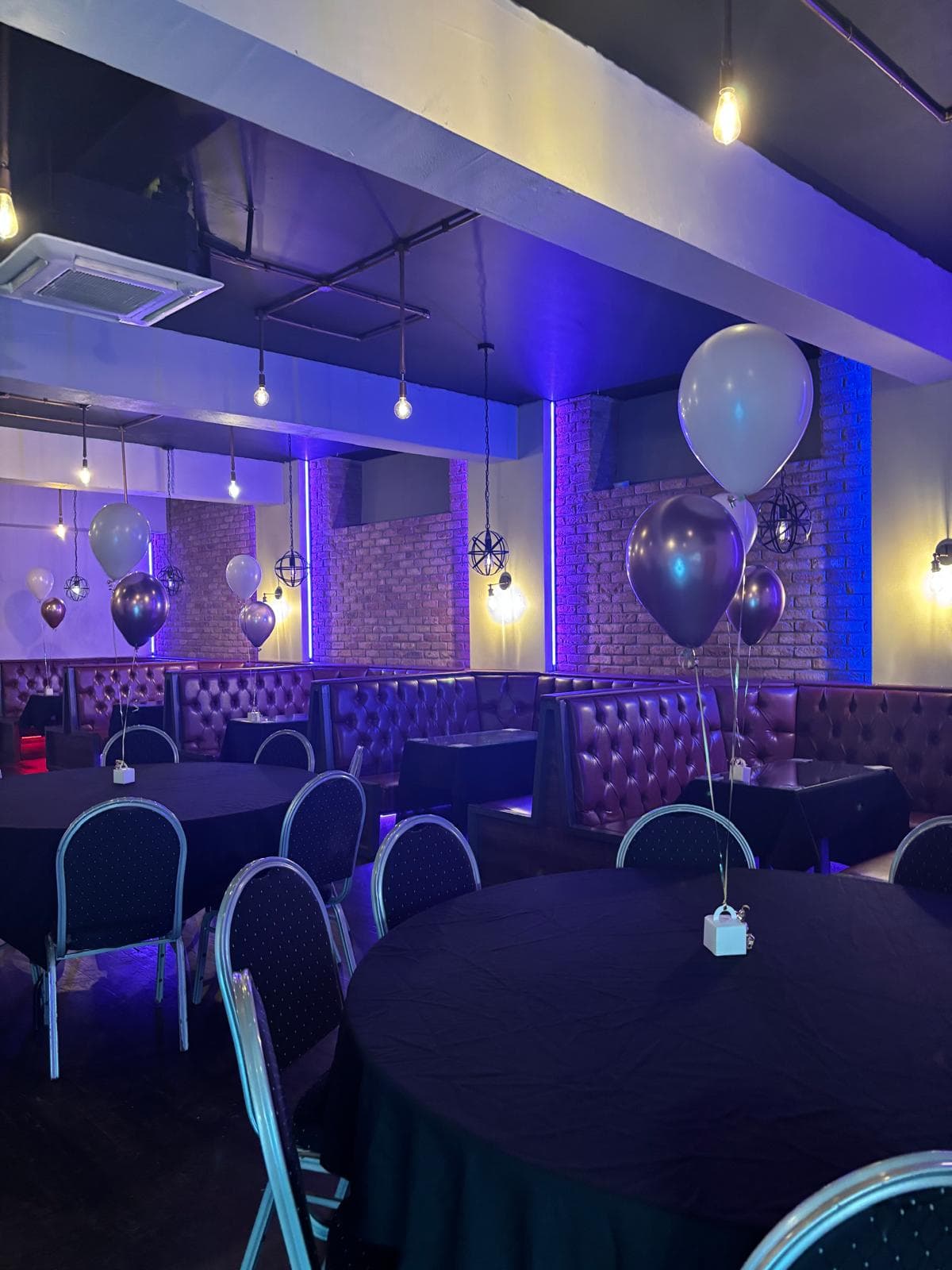 The function room at Gracy's with chesterfield booths, exposed brick and colour lighting