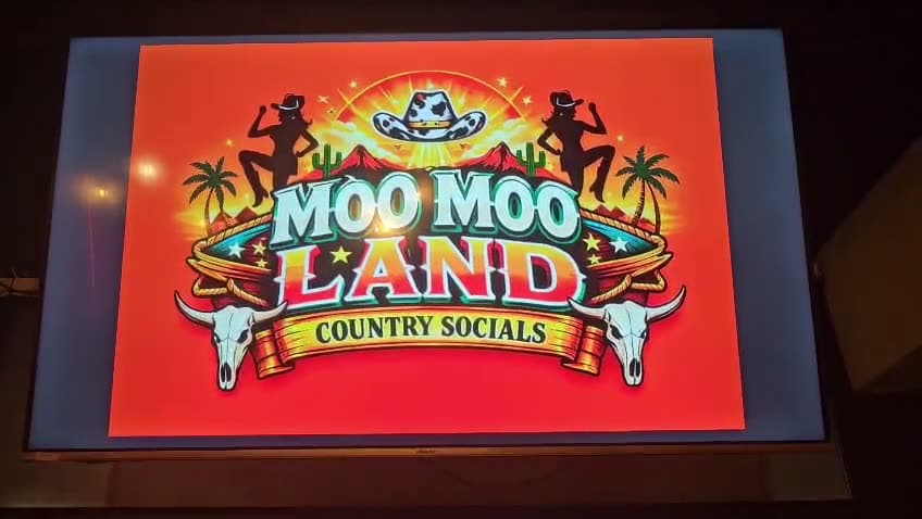 Moo Moo Land country socials title on the big screen, then the western-dressed venue at Gracy's